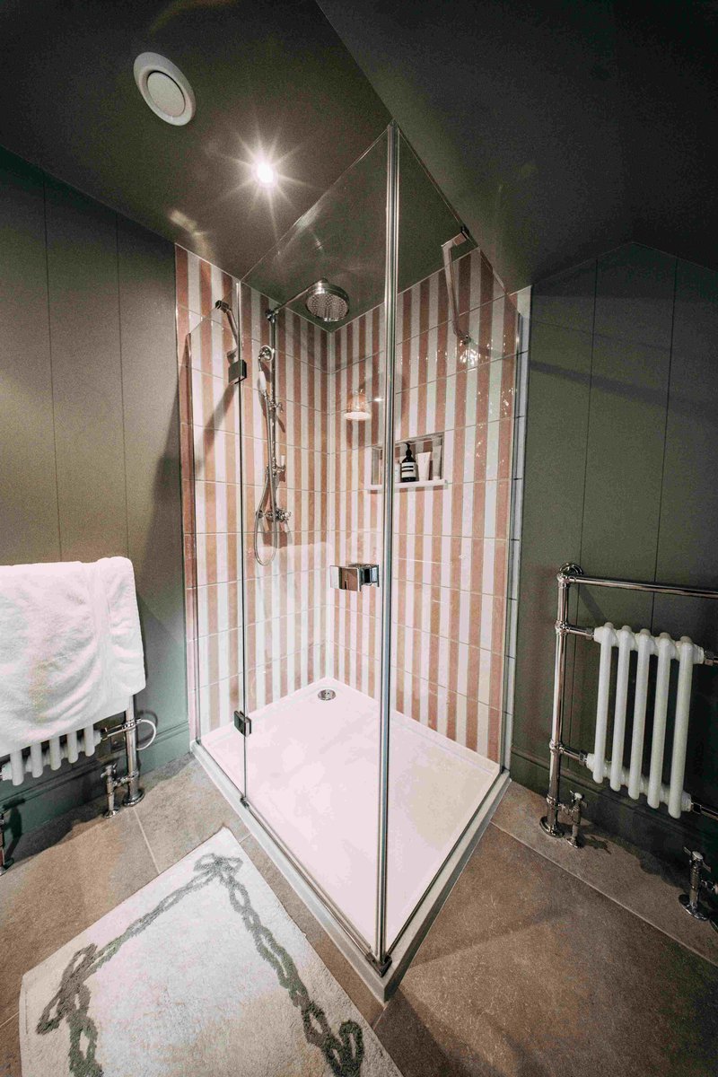 Corner shower with terracotta stripe tile and chrome column