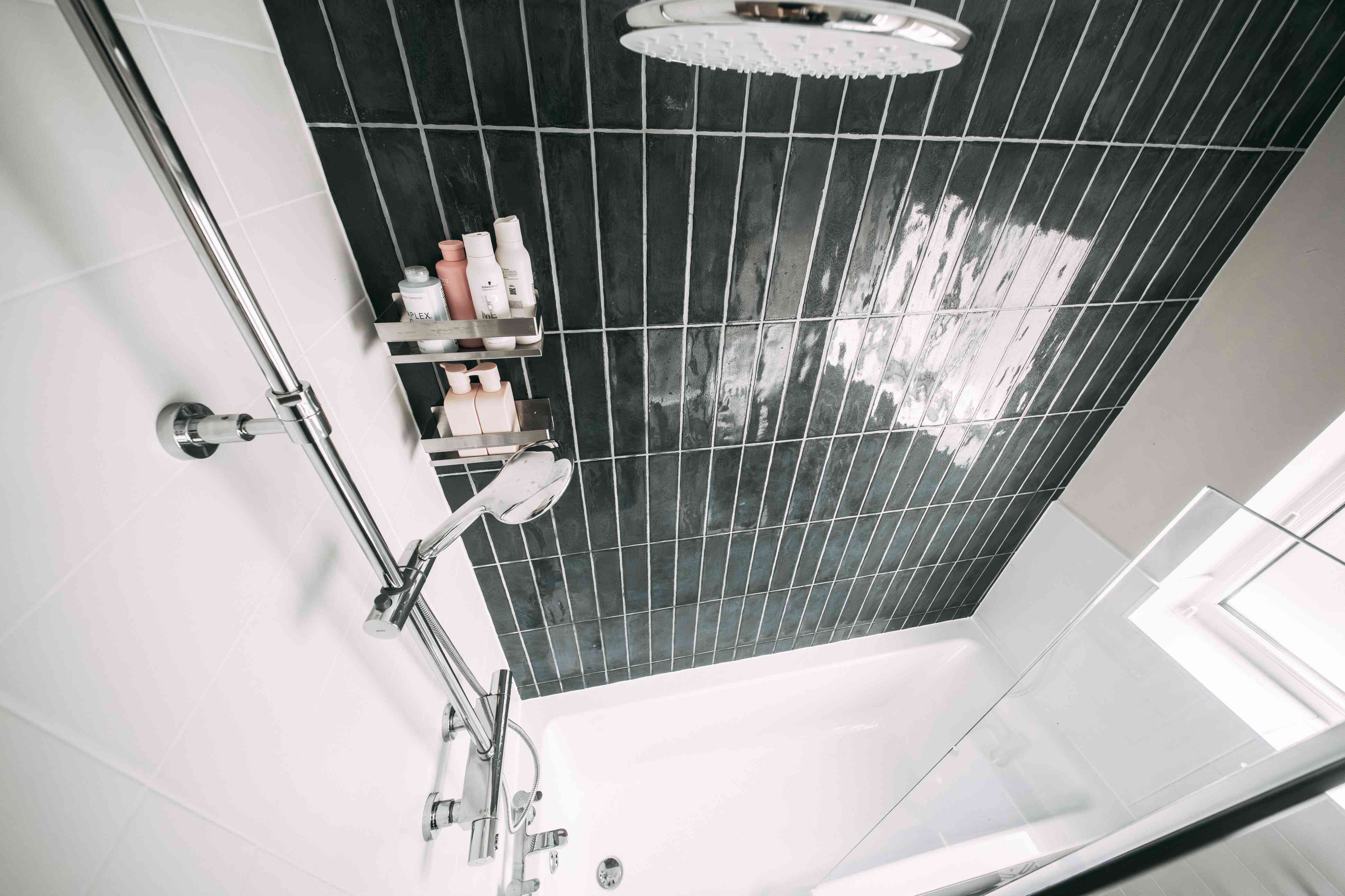Over-bath shower on black tile wall with chrome rainfall